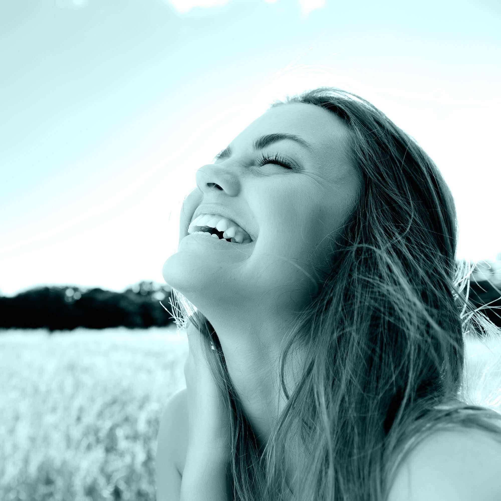 a girl in a meadow laughing with her eyes closed