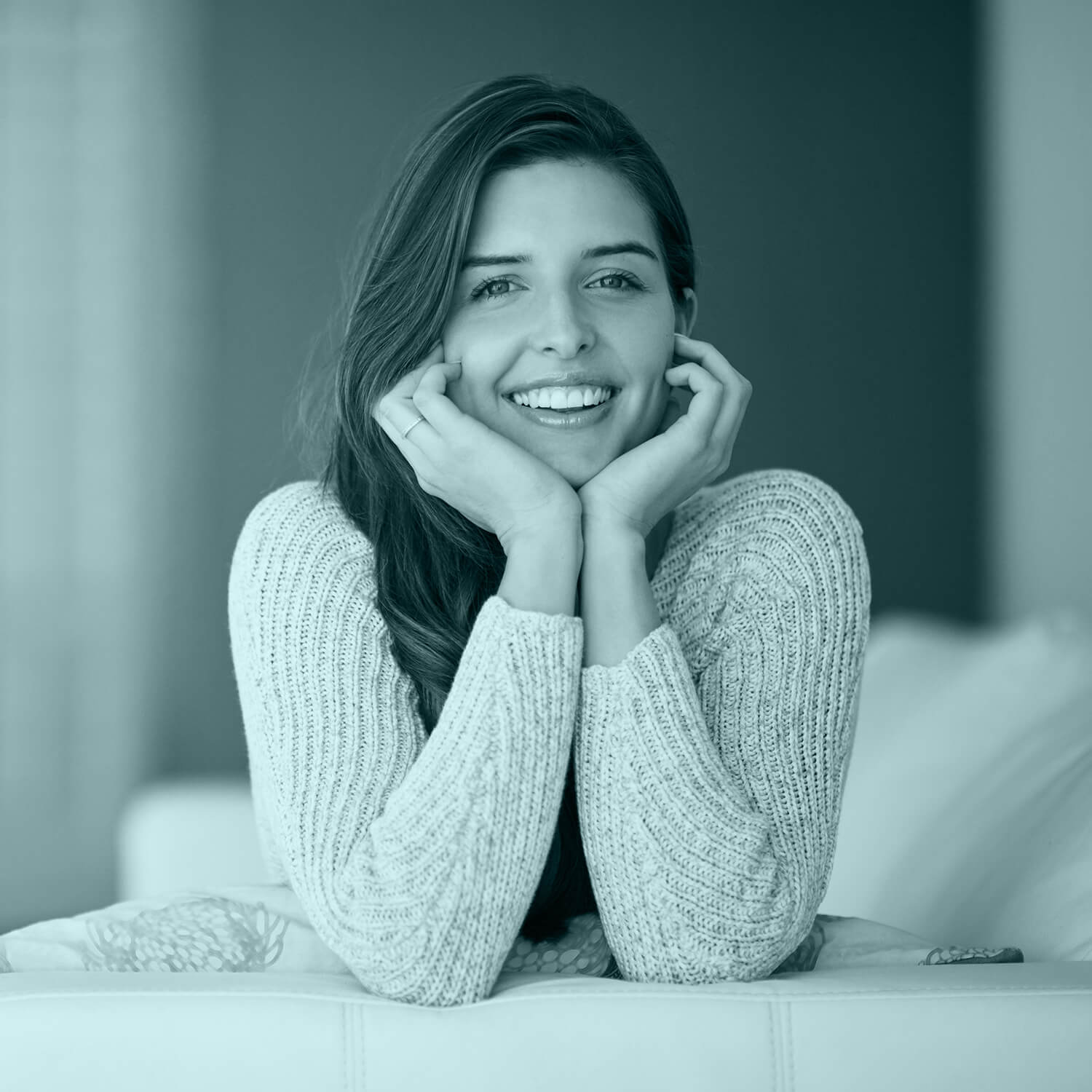 girl smiling sitting on a sofa with her chin resting on her arms