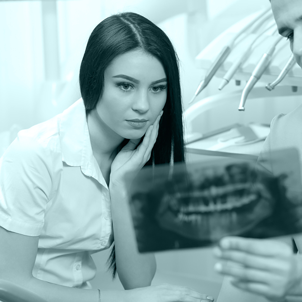 girl is looking at a x-ray of a mouth while her hand is on her cheek