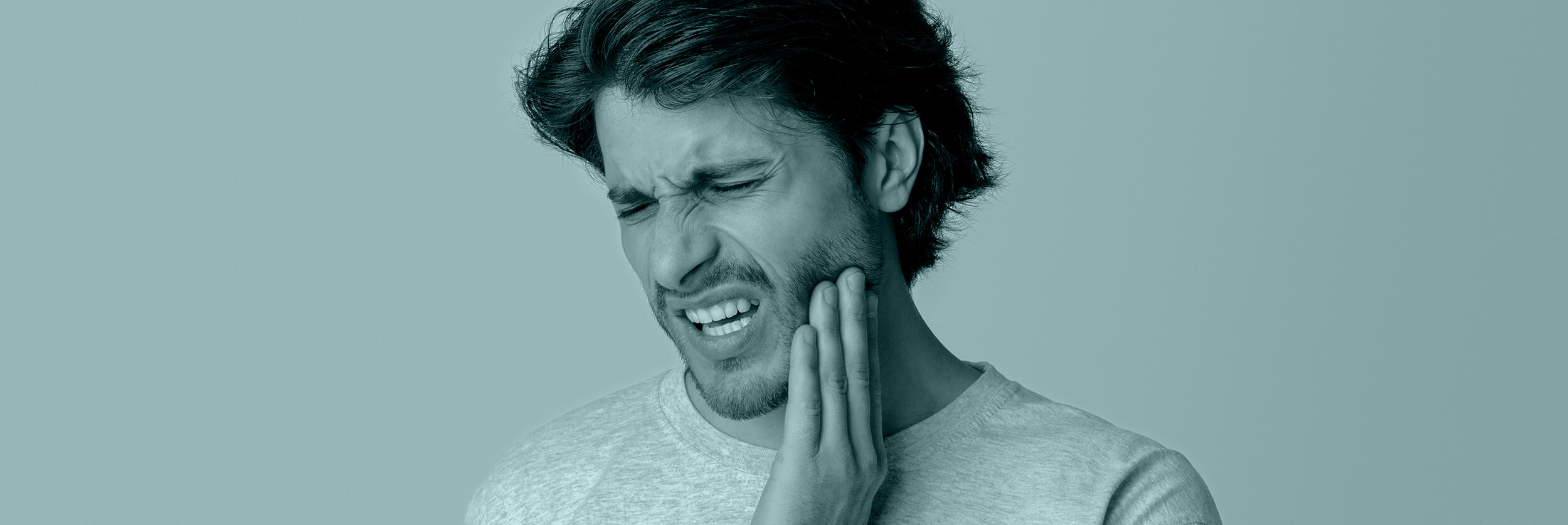 man having a toothache holding his cheek