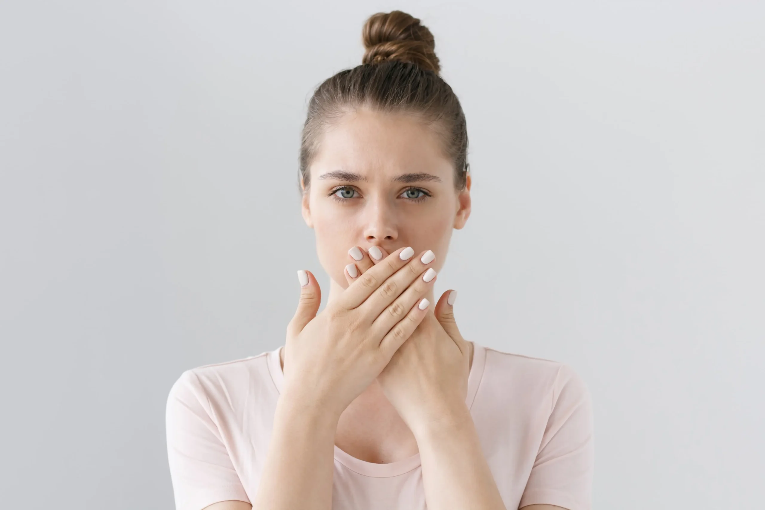 A young woman covering her mouth with both hands.