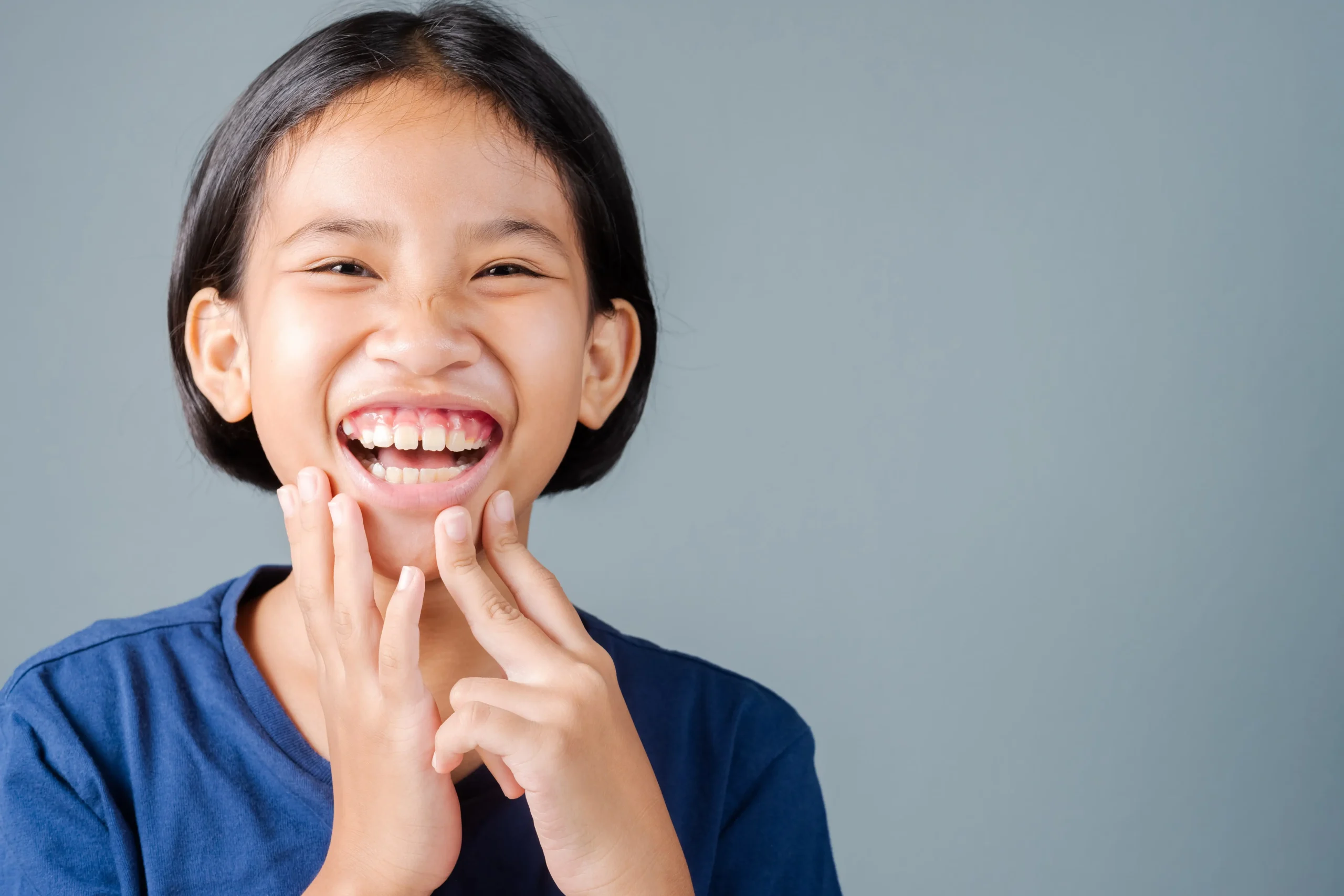 A small child with a gummy smile grinning