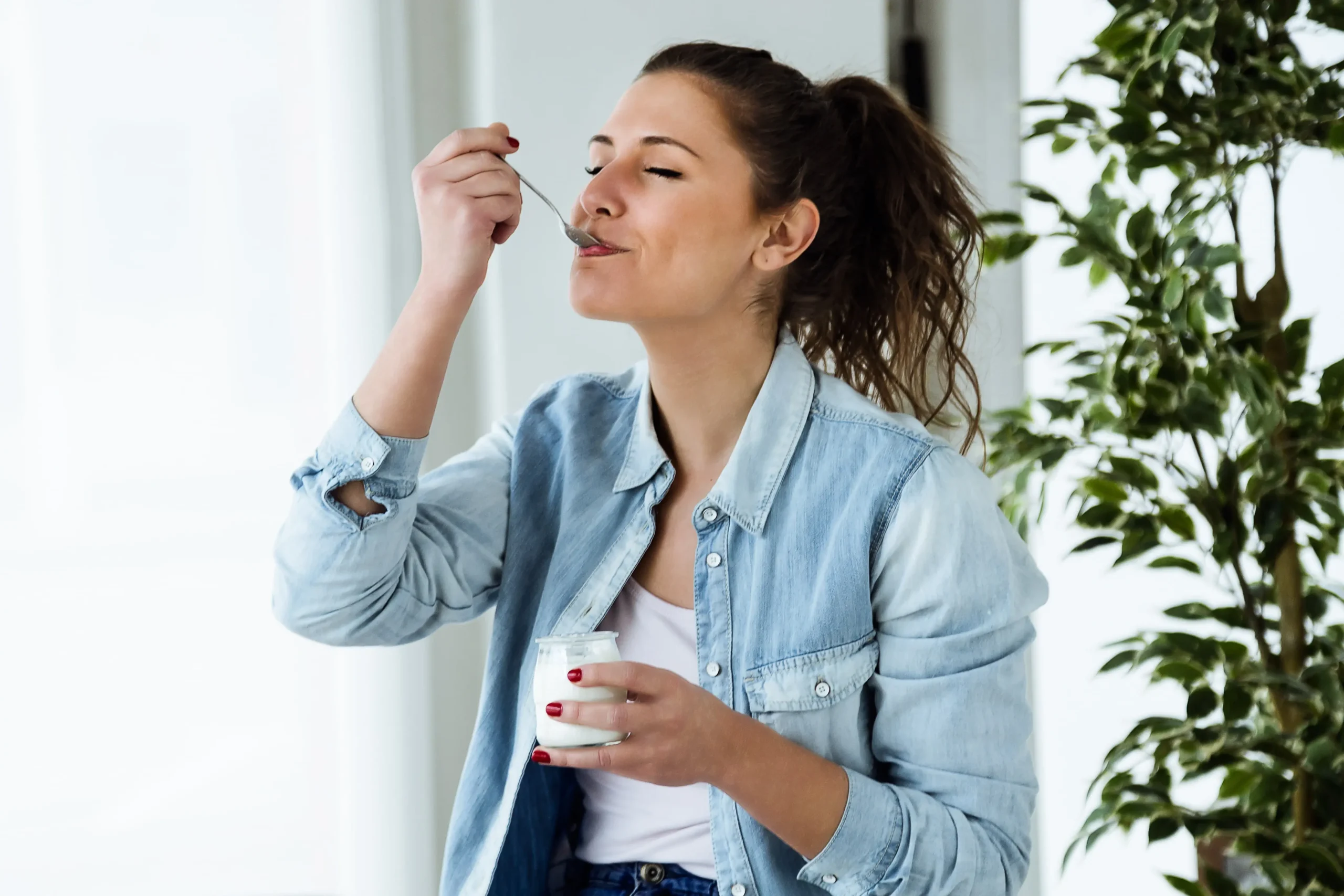 Female smiling and eating a yoghurt